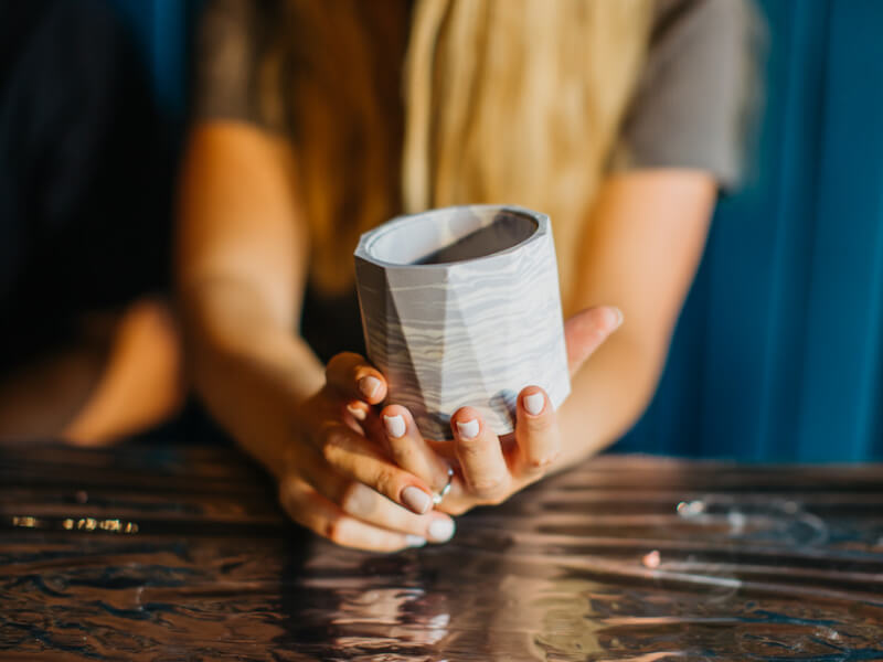 A woman's hands holding a grey resin handmade plant pot